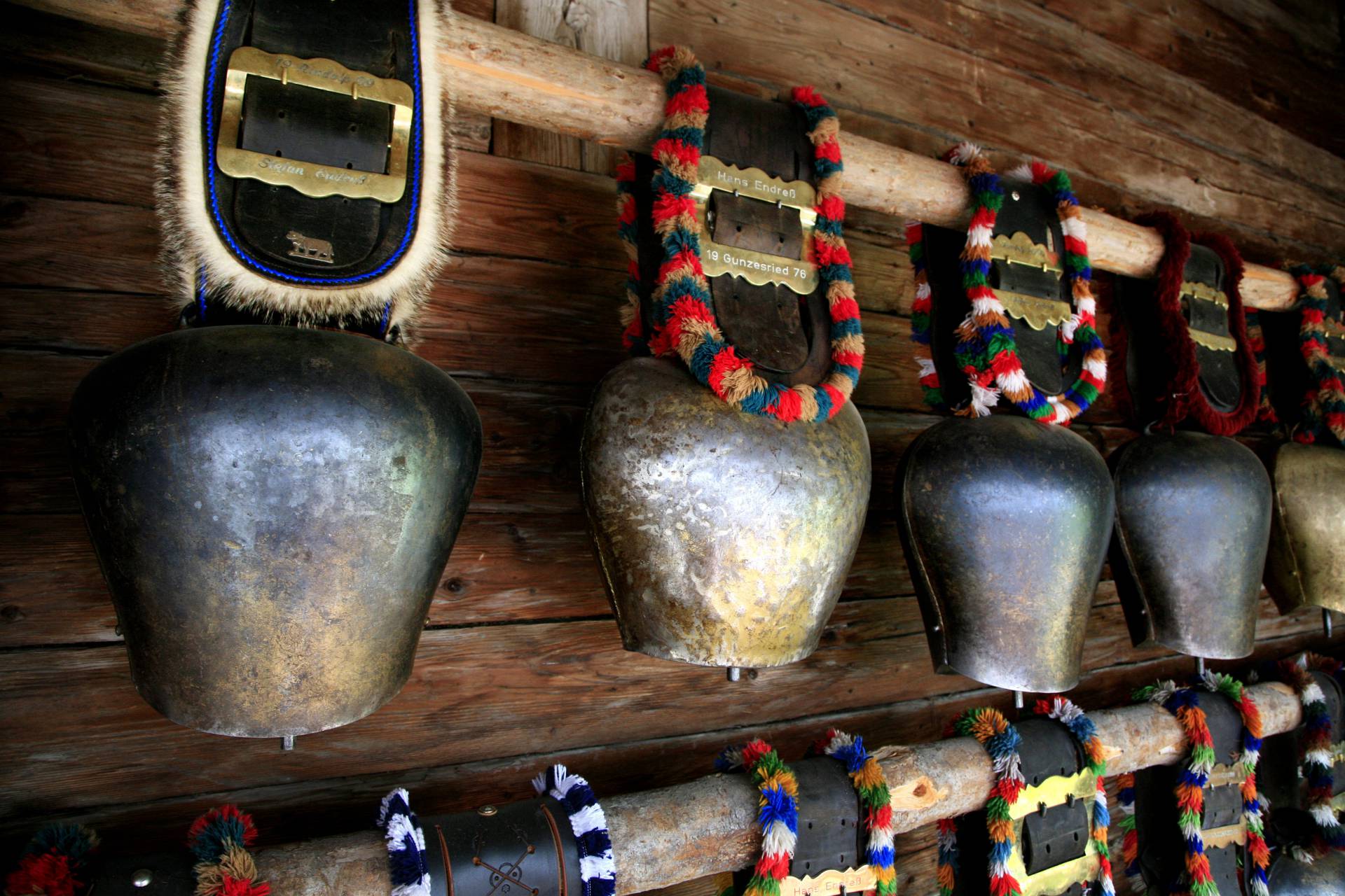 Kuhglocken hängen an einer Holzwand