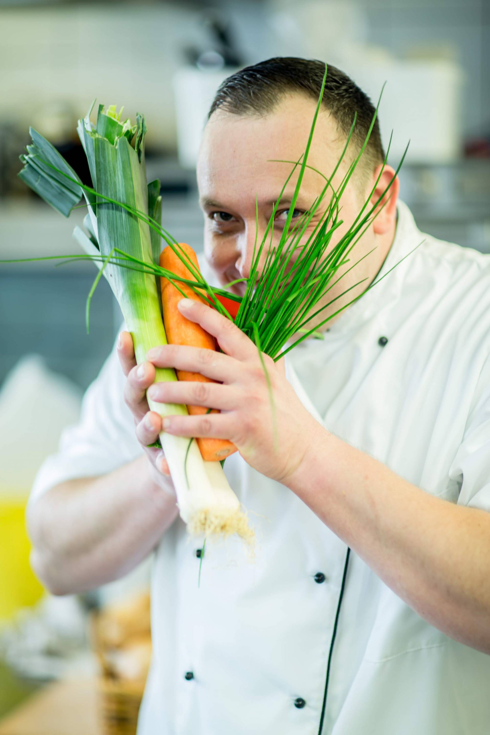 Koch hält frisches Gemüse und Kräuter