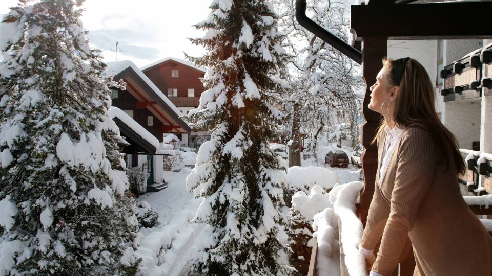 Frau schaut in die Sonne im Winter vom Balkon